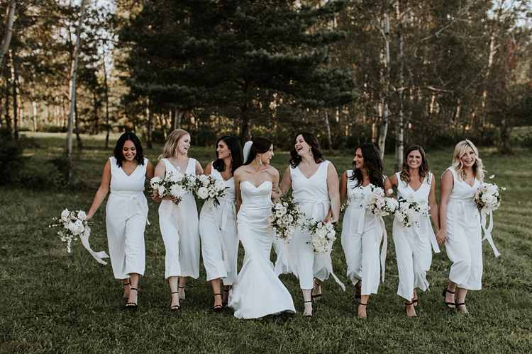 Bride and bridesmaids walking through forest wearing all white