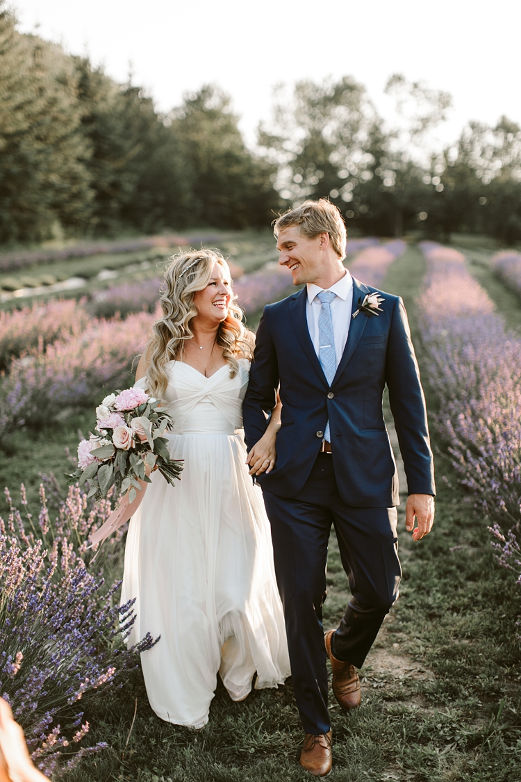 Couple walk through lavender field on their wedding day